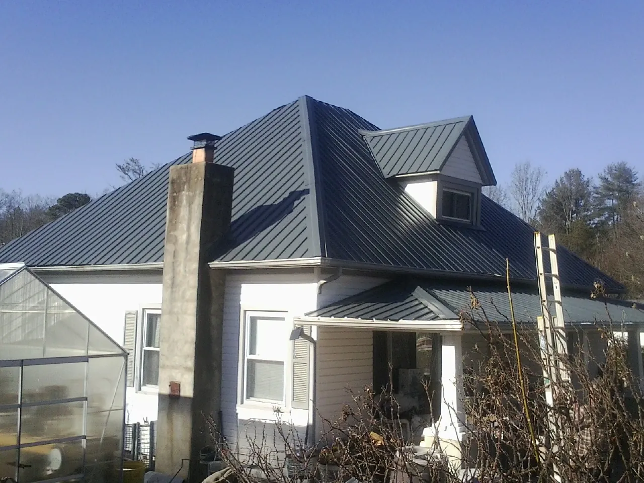 Dark blue standing seam metal roof on a white farmhouse with dormer — Slate & Tile Roof Repair by Roofing Brothers in Saluda
