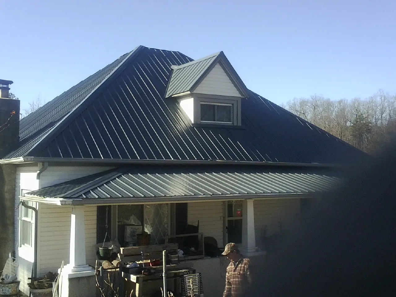 Dark blue standing seam metal roof with a dormer above a front porch in Saluda