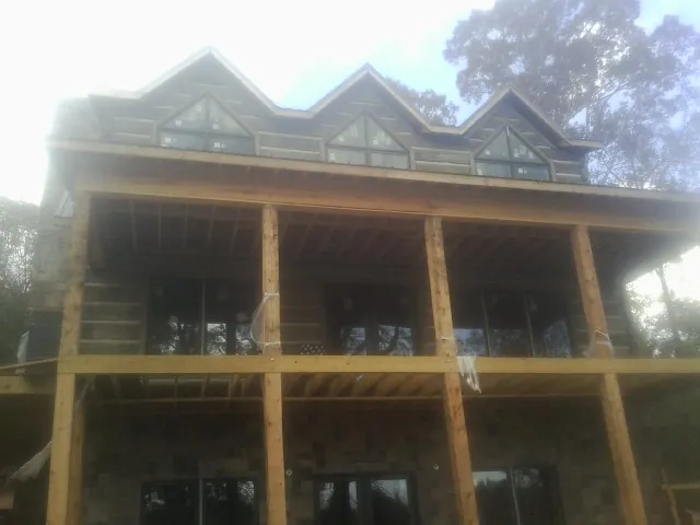 Dormers and porch framing on a large log home under construction — Roof Coating work by our crew in Saluda
