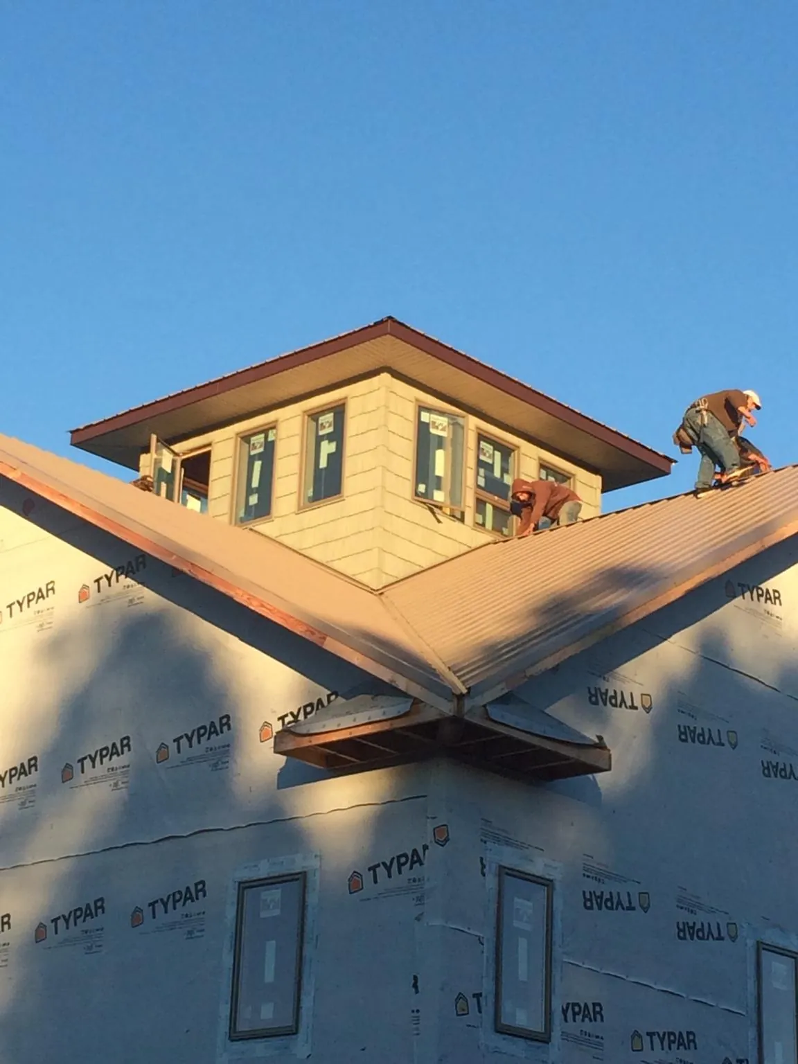 Roofers working around a rooftop cupola on a new metal roof at sunset — Roof Waterproofing in Saluda by Roofing Brothers